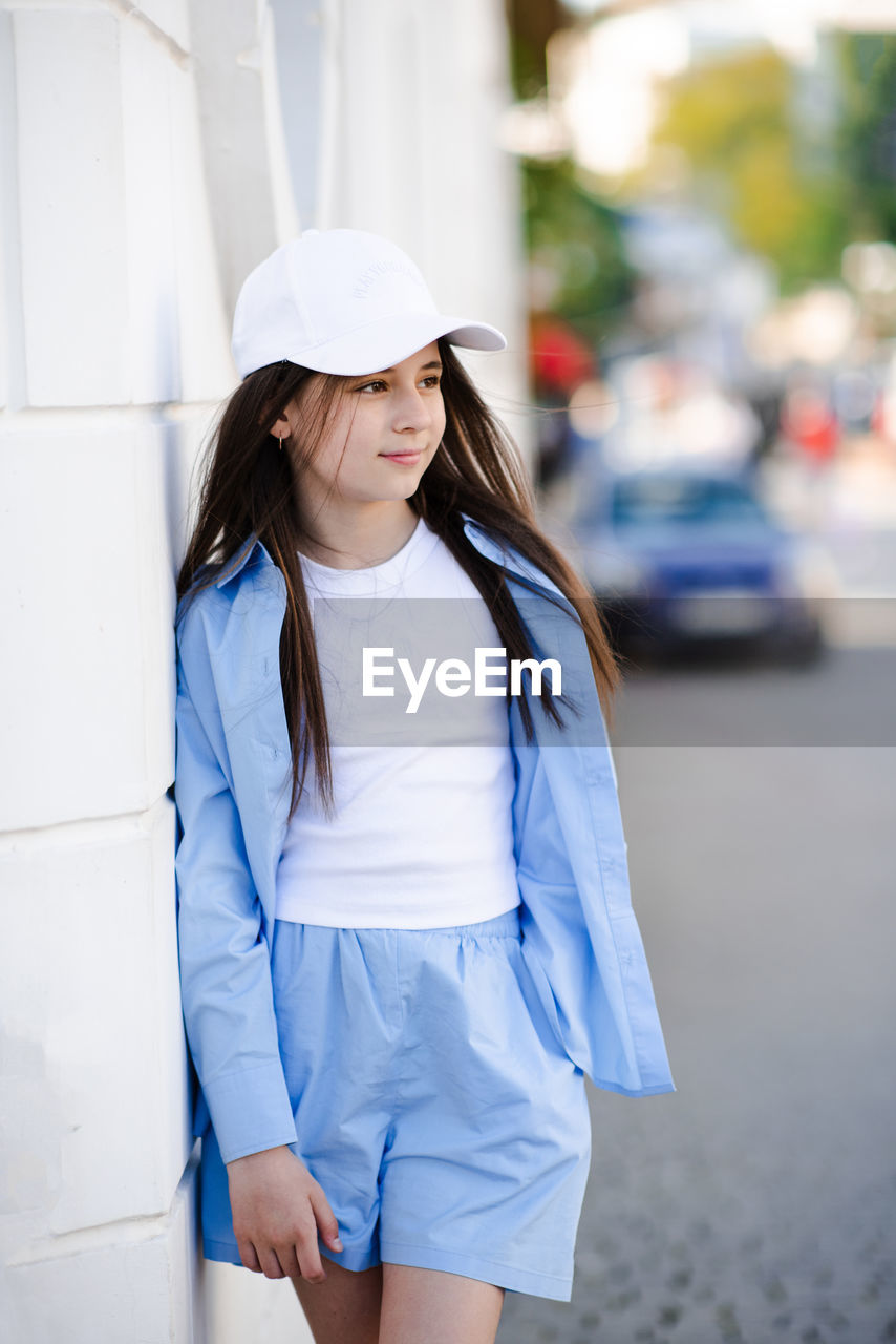 portrait of young woman standing on street in city