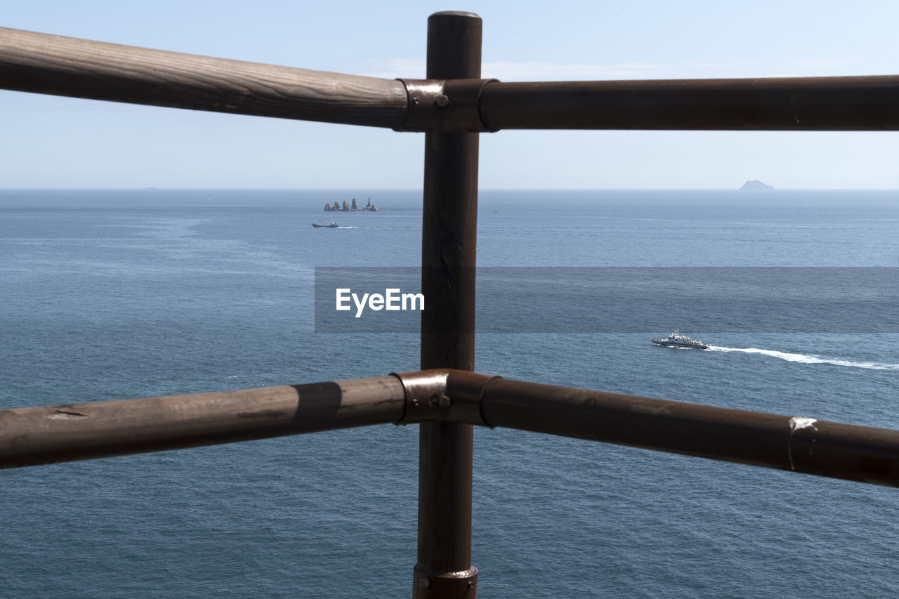 Close-up of railing by sea against sky