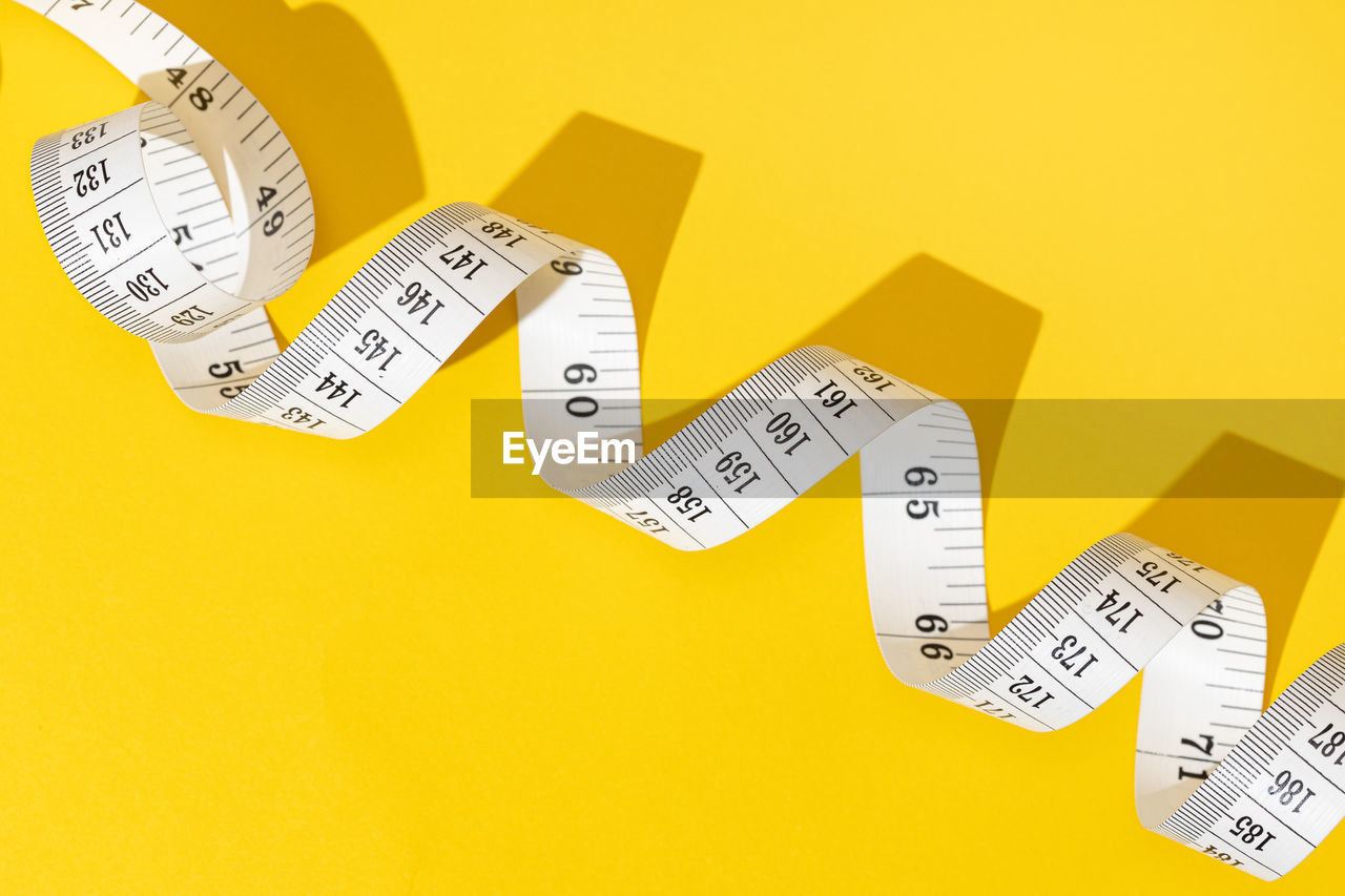 font, yellow, number, business, finance, colored background, text, studio shot, instrument of measurement, indoors, no people, wealth, tape measure
