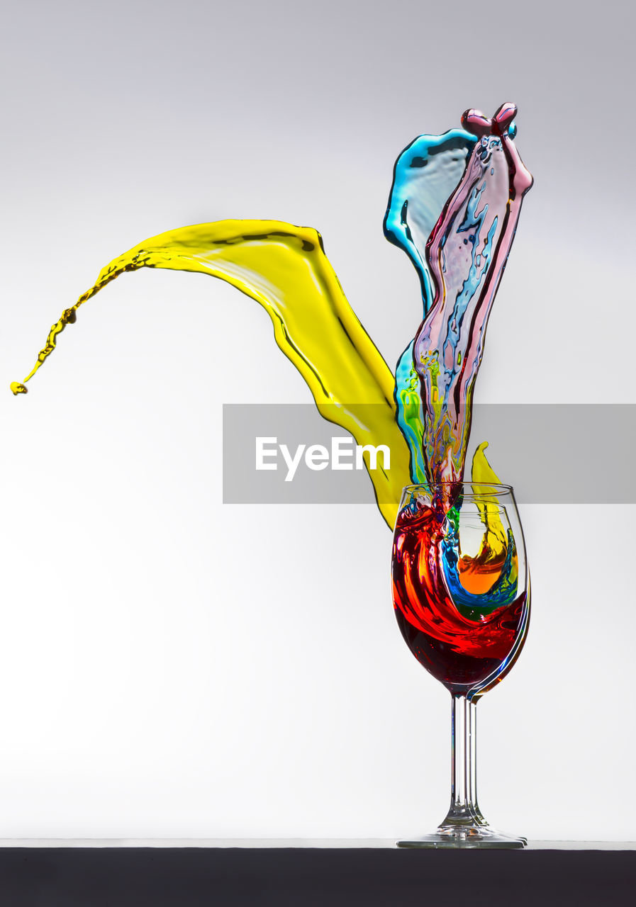 Close-up of splashing liquid in wineglass against white background