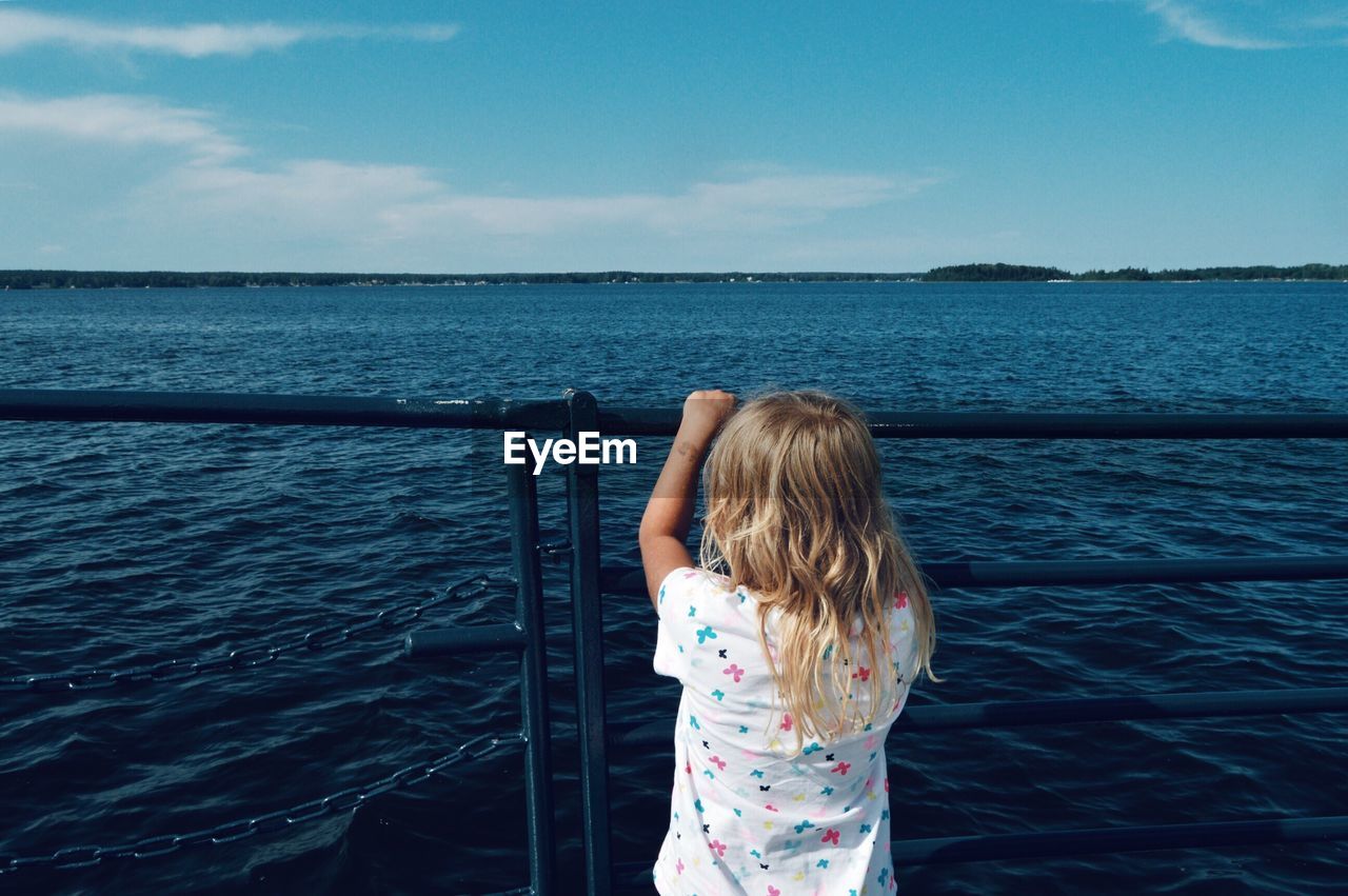 Rear view of girl looking at sea against sky