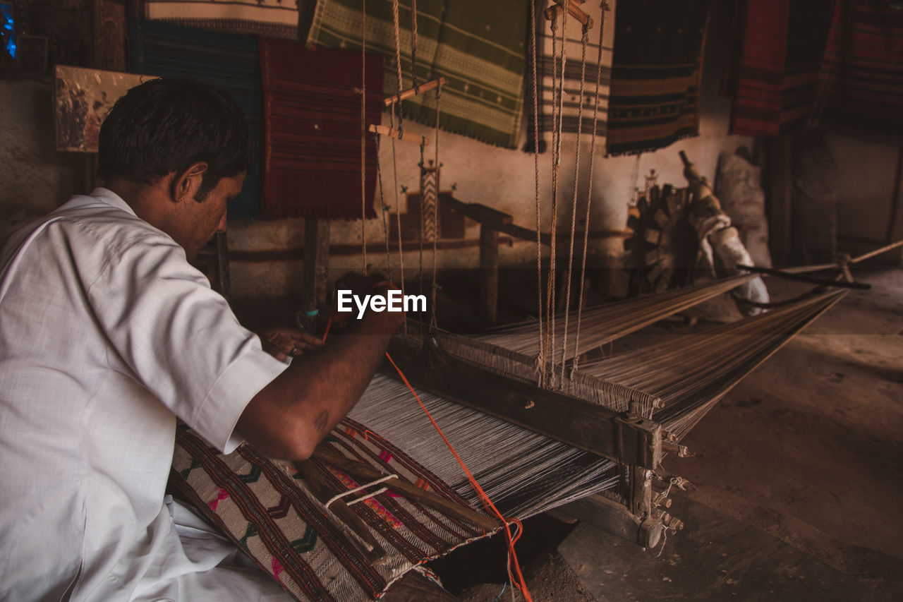 Side view of man working as a weaver