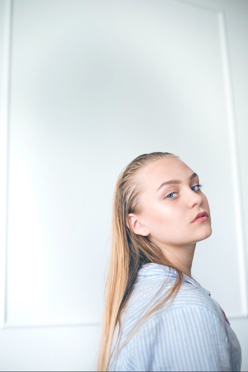 Portrait of beautiful young woman against white wall