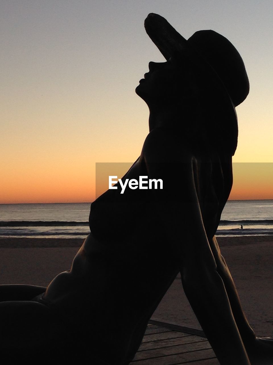 Side view of silhouette woman relaxing at beach during sunset