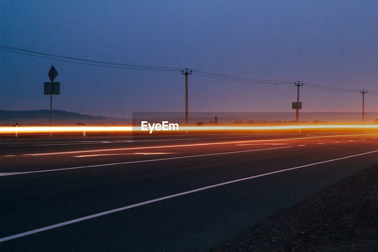 Light trails on road against clear sky at night