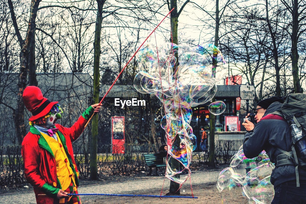 REAR VIEW OF PEOPLE AGAINST MULTI COLORED TREE