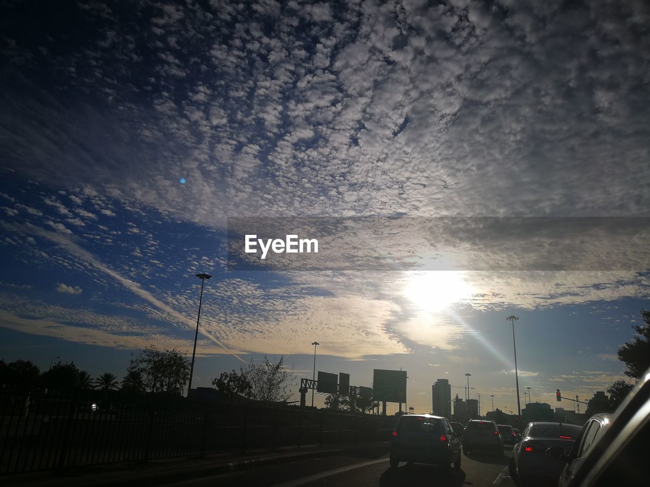 CARS ON ROAD AGAINST SKY IN CITY