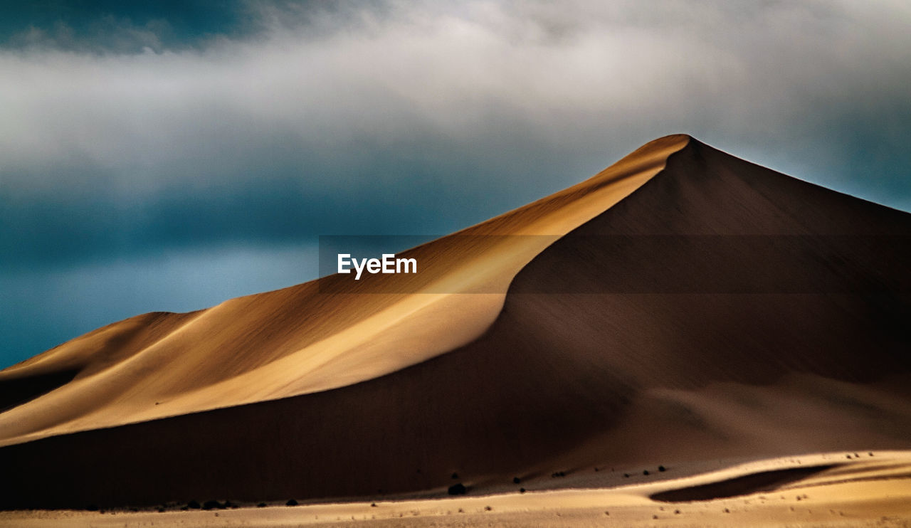 Low angle view of sand dunes against sky