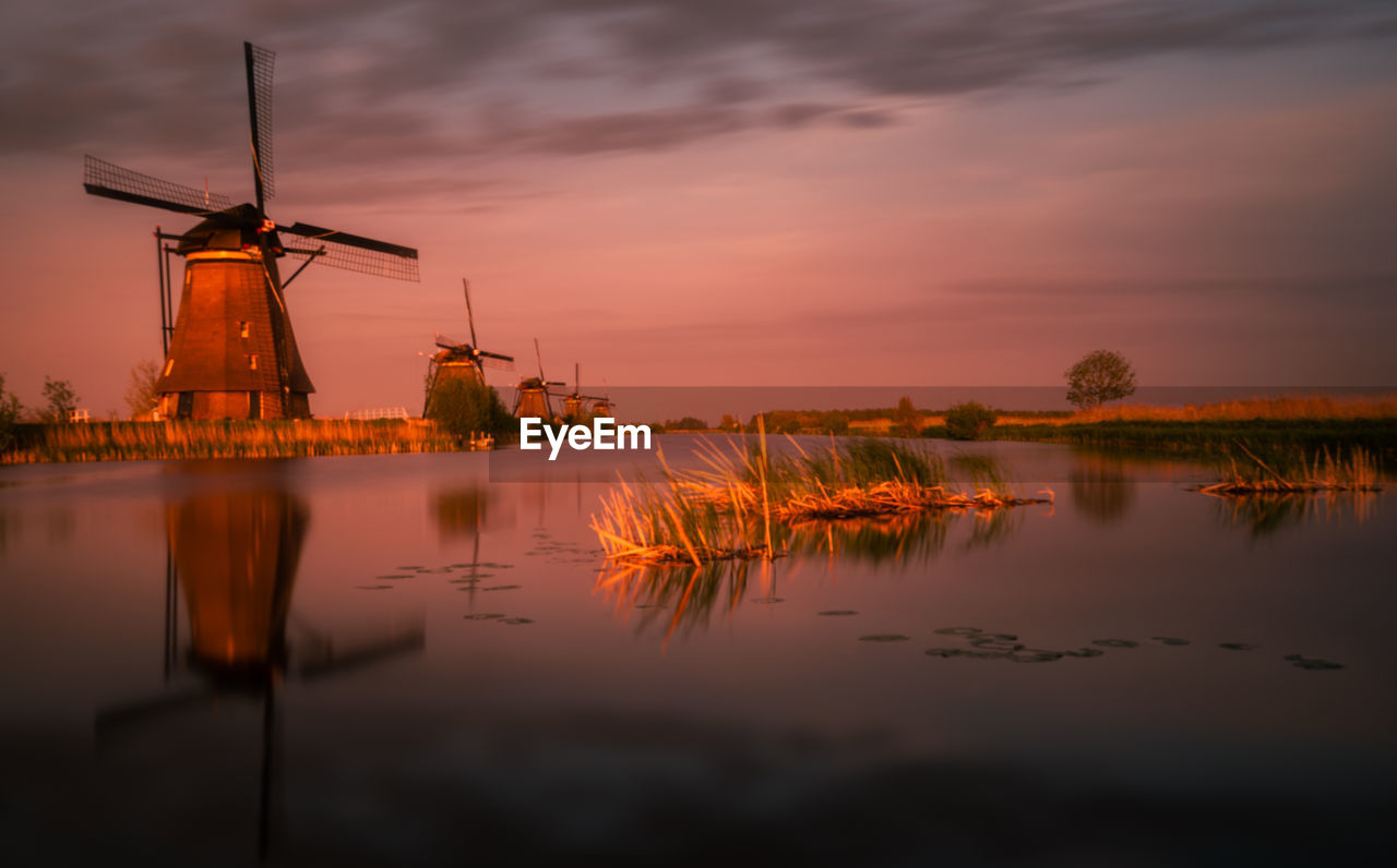 Traditional windmill against sky during sunset