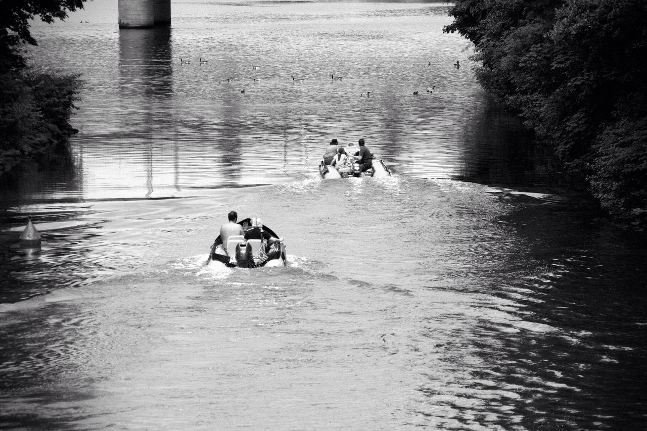 Rear view of people in speedboats at calm lake