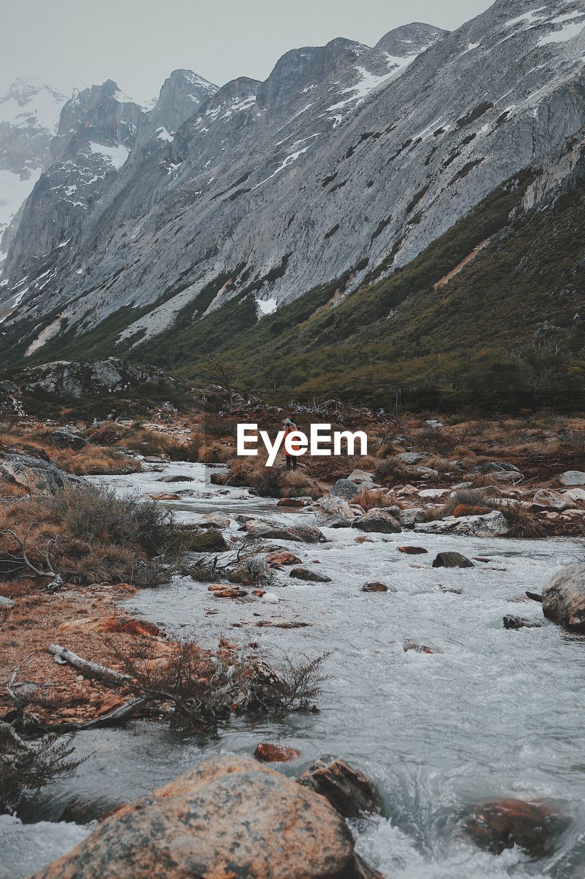 SCENIC VIEW OF WATERFALL AGAINST MOUNTAINS