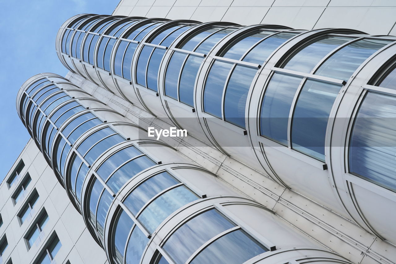 LOW ANGLE VIEW OF MODERN GLASS BUILDING AGAINST SKY