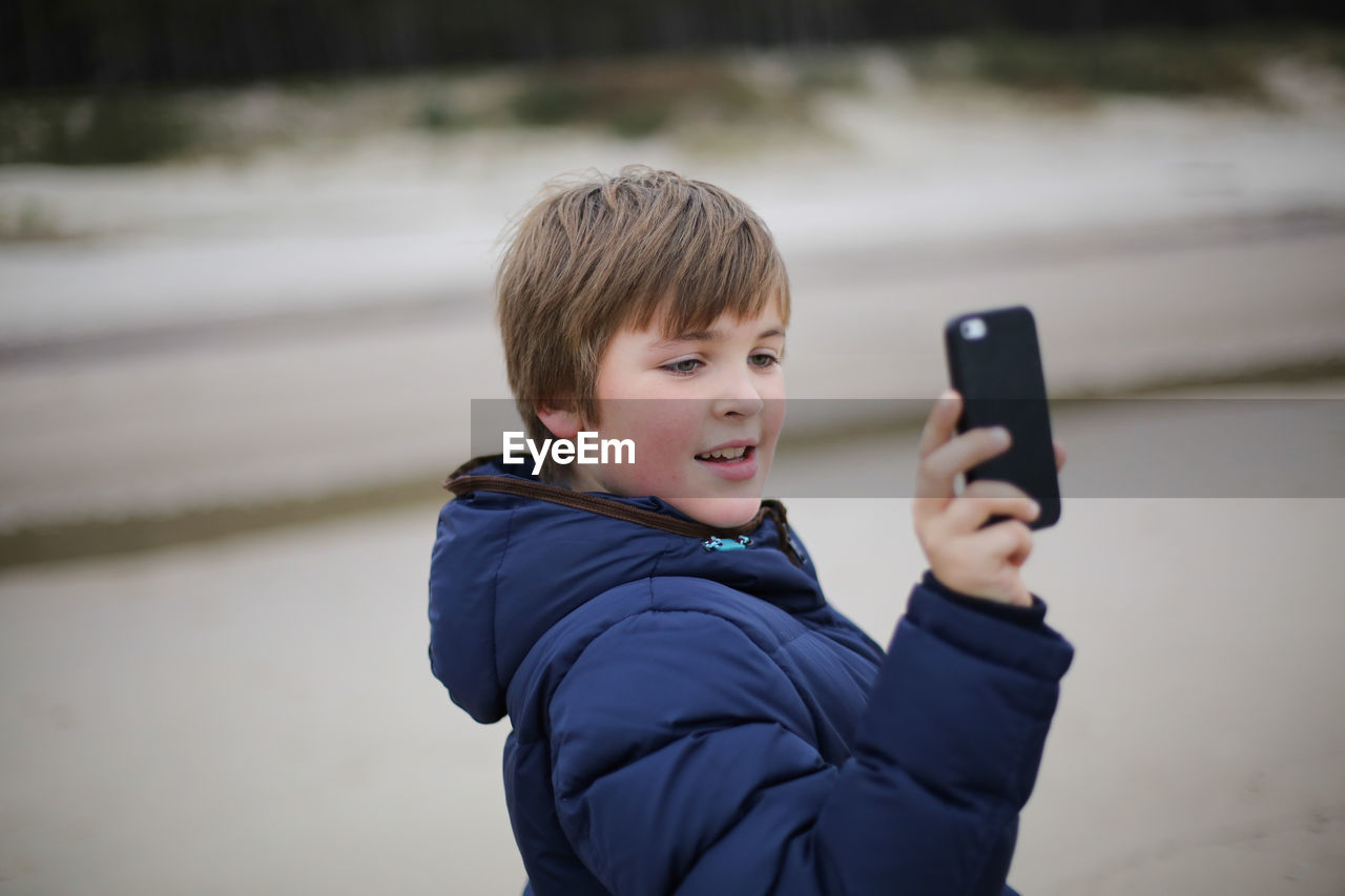 Close-up of boy photographing with mobile phone