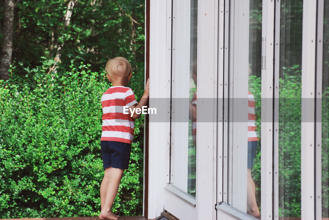 Rear view of boy standing by plants