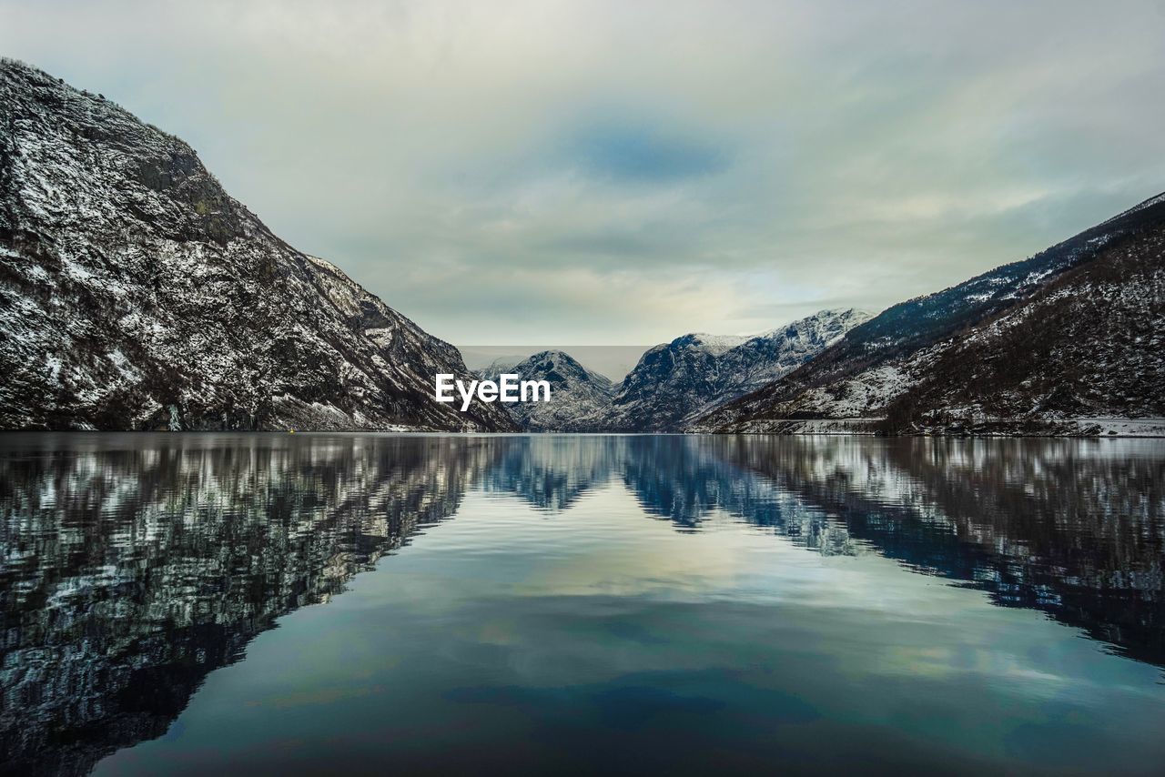 Scenic view of lake by mountains against sky