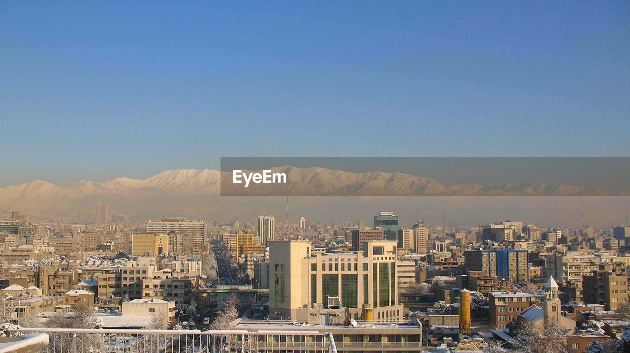 Aerial view of buildings in city against clear sky