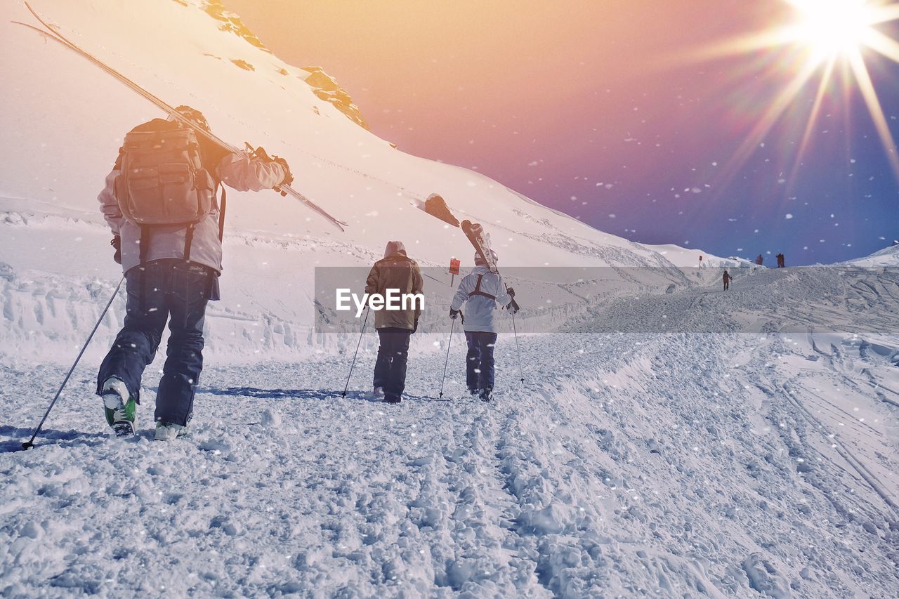 Rear view of people walking on snow covered mountain during snowing