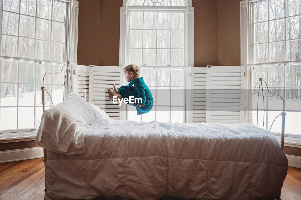 Little girl jumping on a bed in the air