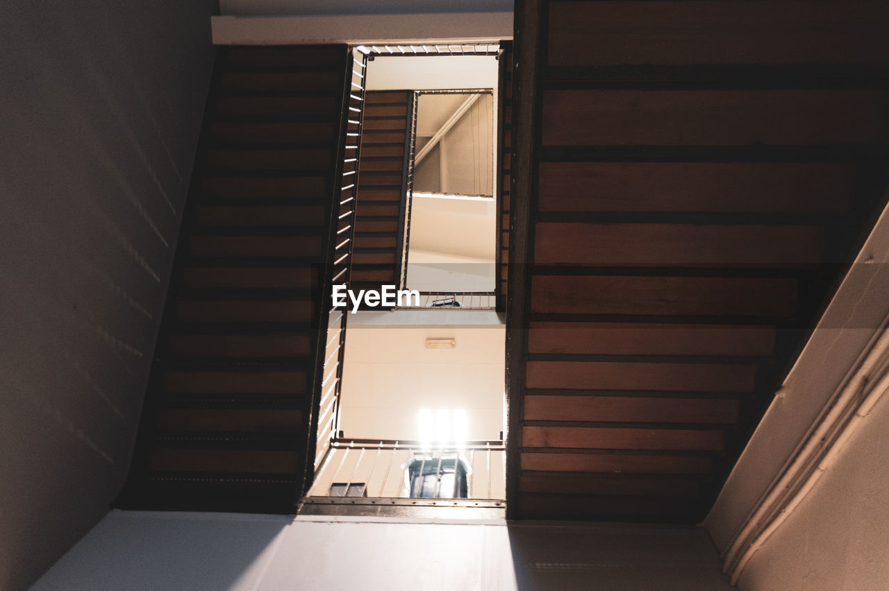 LOW ANGLE VIEW OF STAIRCASE IN ILLUMINATED BUILDING