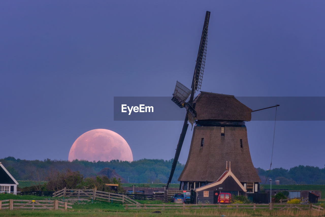 Traditional windmill on field against clear sky moonrise 