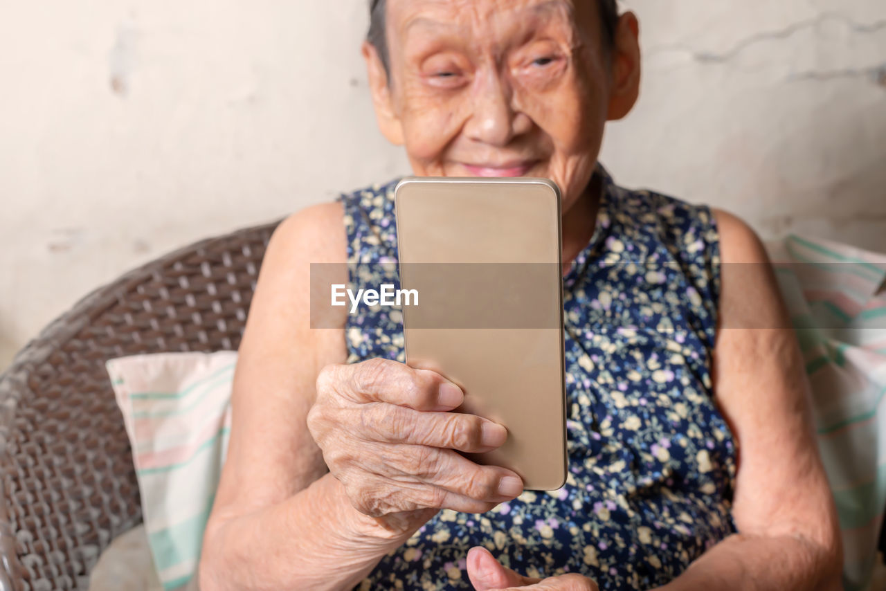 Senior woman holding mobile phone at home