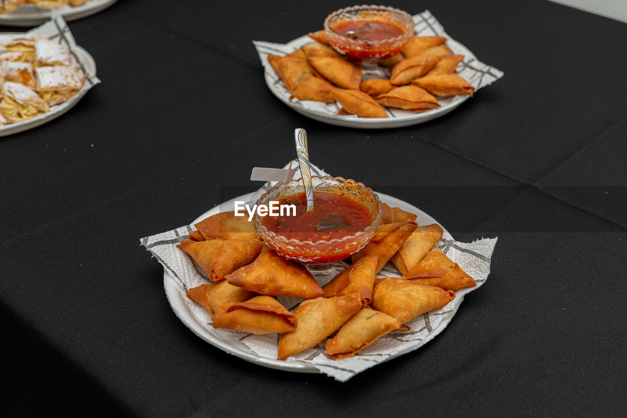 High angle view of deep fried samoosas and a chutney on a tray.