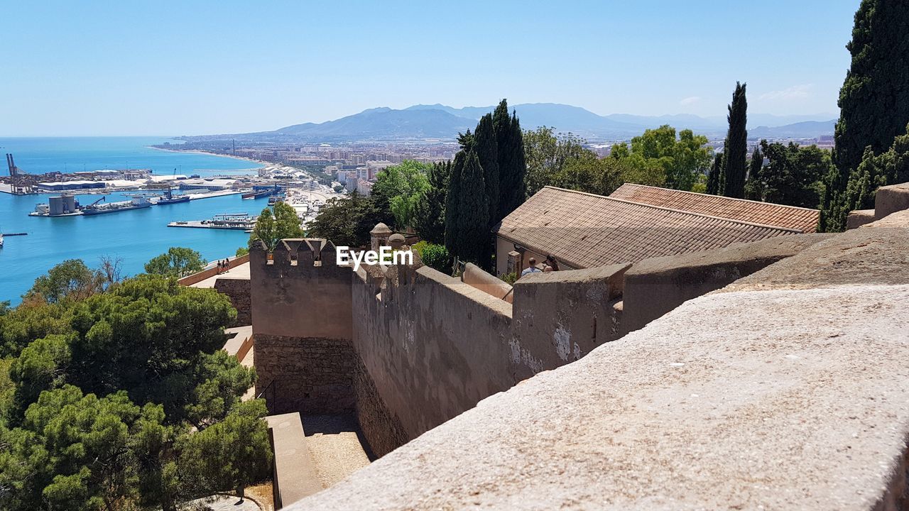 water, vacation, architecture, sea, nature, built structure, sky, tourism, building exterior, travel destinations, scenics - nature, tree, land, travel, building, clear sky, mountain, coast, no people, day, plant, beach, sunny, blue, roof, sunlight, house, outdoors, high angle view, nautical vessel, beauty in nature, history, environment, landscape, the past, transportation, city, tranquility, residential district
