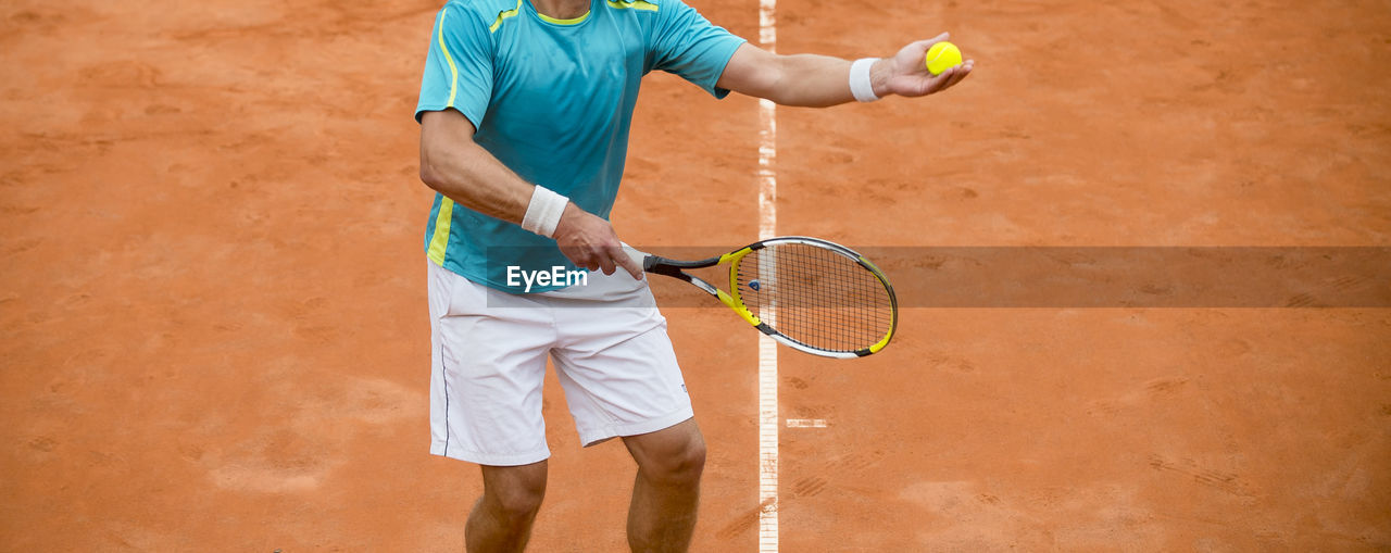 Midsection of man playing tennis