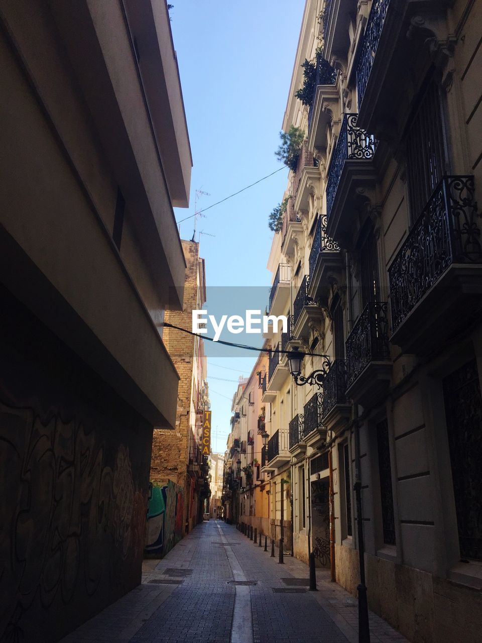 LOW ANGLE VIEW OF NARROW STREET AMIDST BUILDINGS