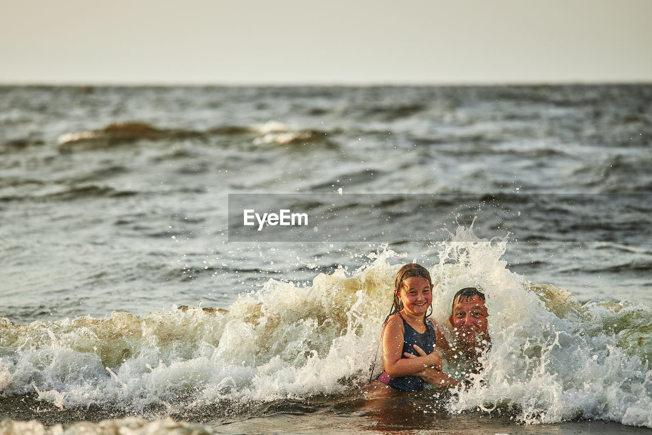 Little girl and her dad playing with waves in the sea. family summer vacations. family play in sea