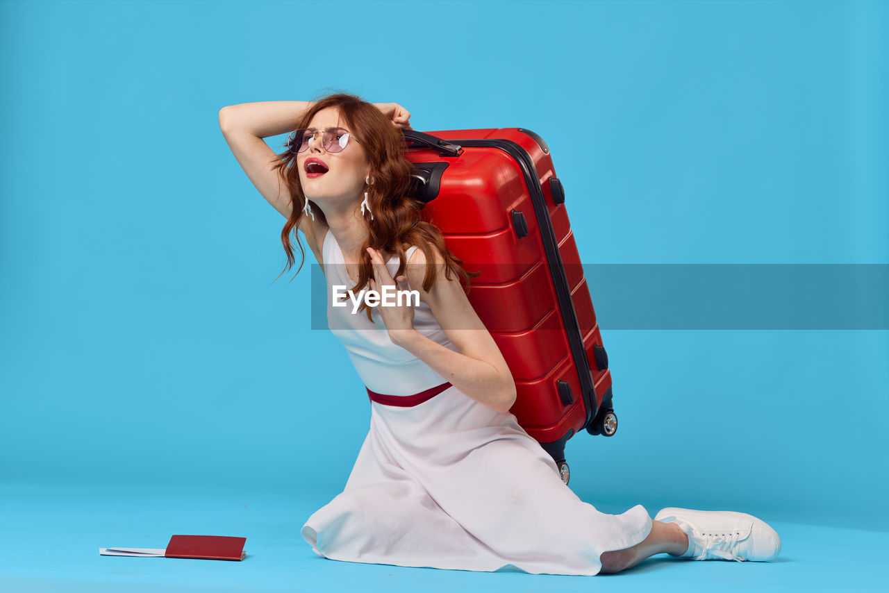 Young woman with umbrella against blue background