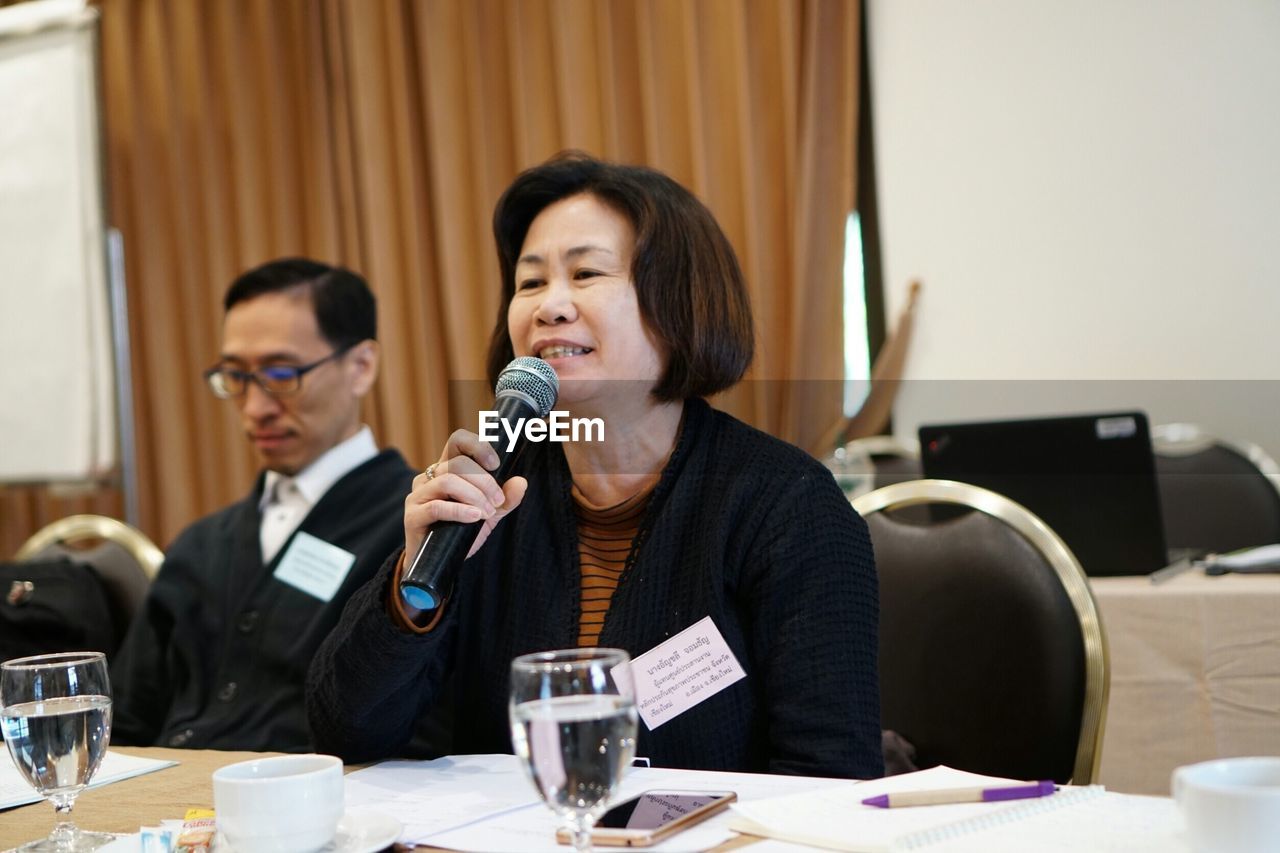 Businesswoman speaking on microphone at desk in office