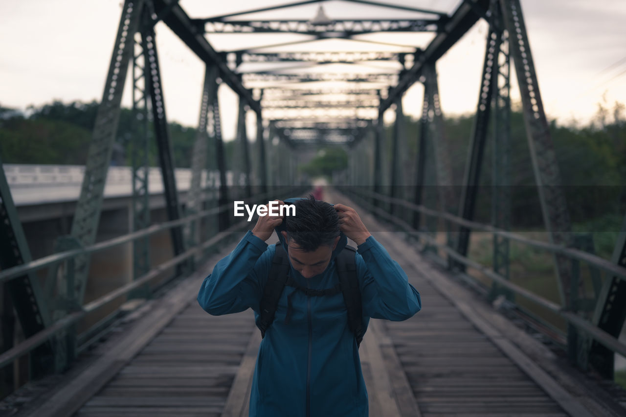 Young man backpacker walking cross the bridge and wearing hoodie  , freedom and recreation concept