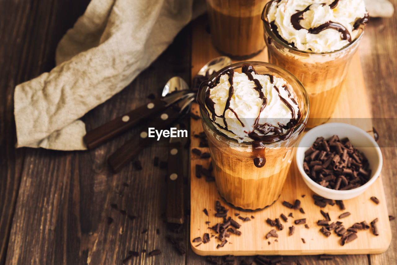 Homemade coffee coctail with whipped cream and liquid chocolate on rustic wooden background