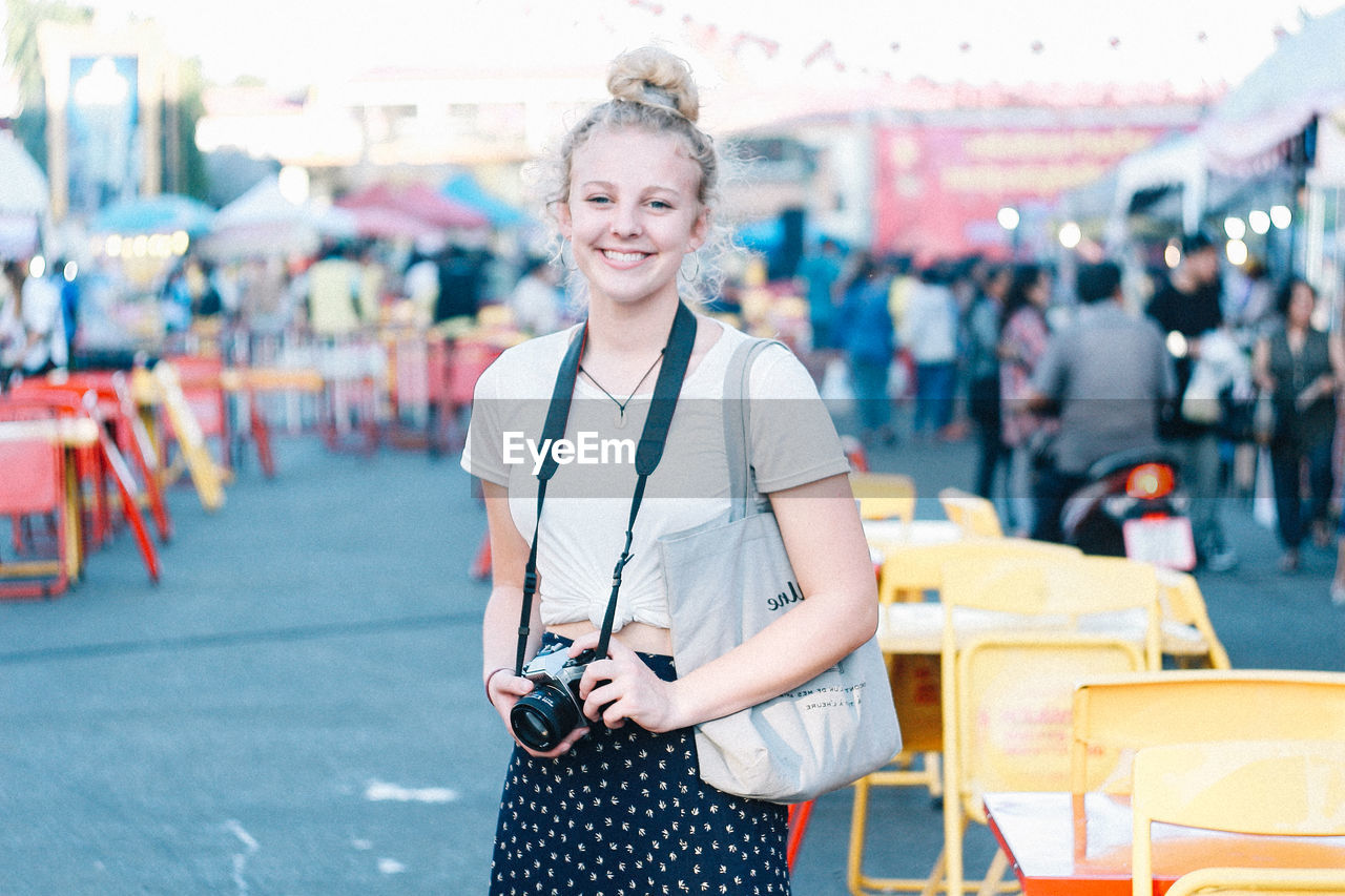 Portrait of smiling young woman standing in city