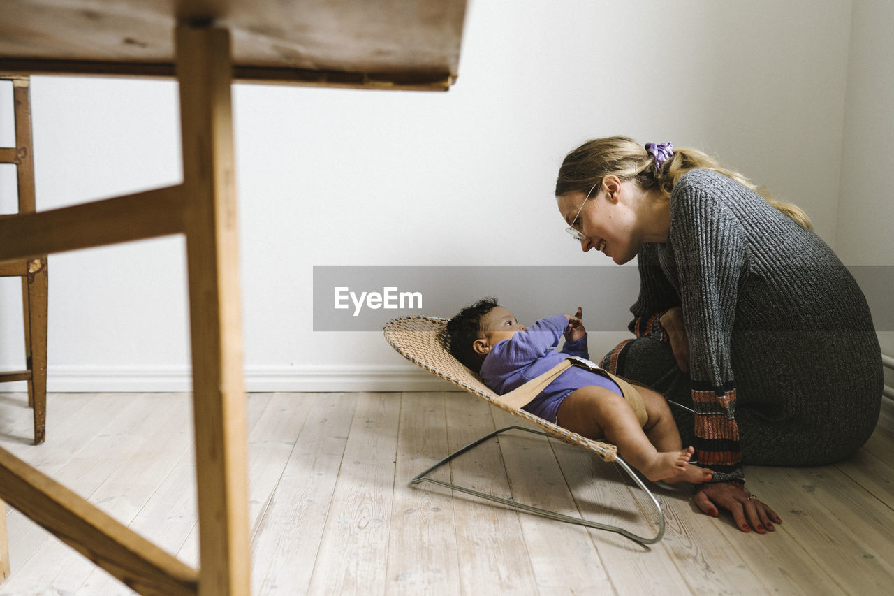 Mother looking at baby lying in bouncer