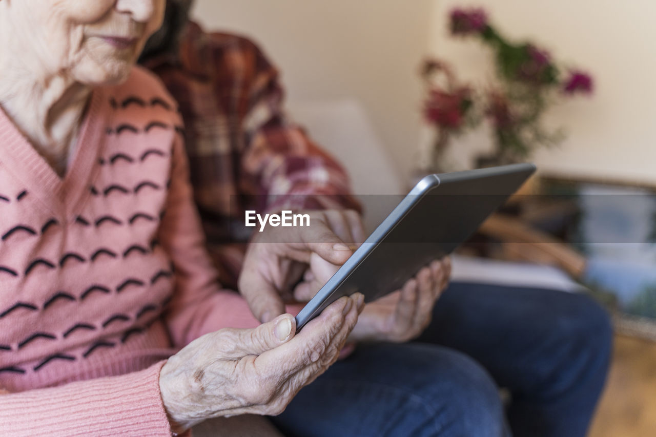 Mature man teaching tablet pc to senior woman at home