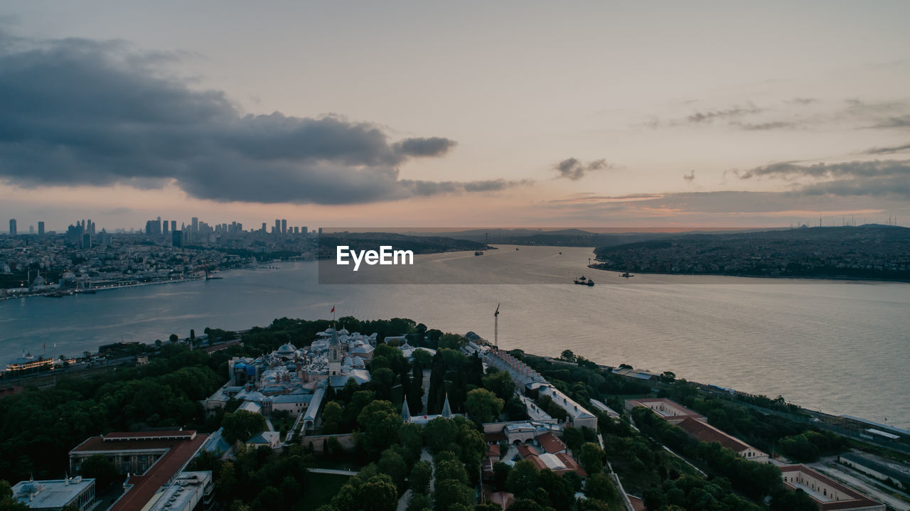 HIGH ANGLE VIEW OF CITYSCAPE AGAINST SKY DURING SUNSET