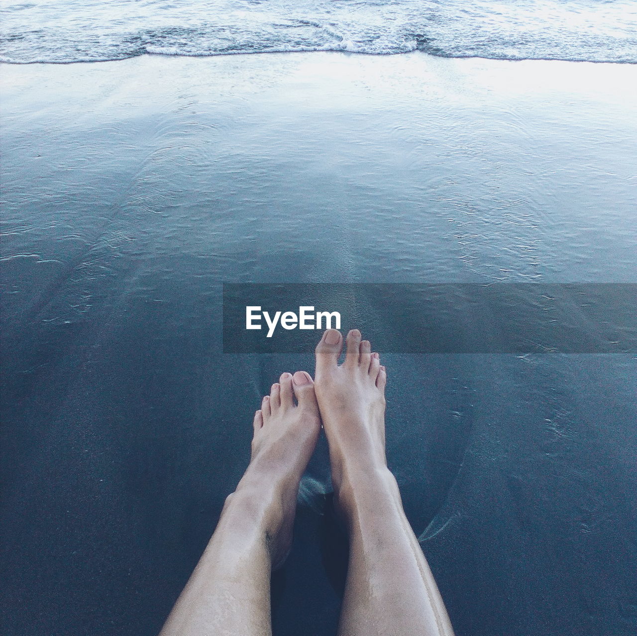 Low section of woman on shore at beach