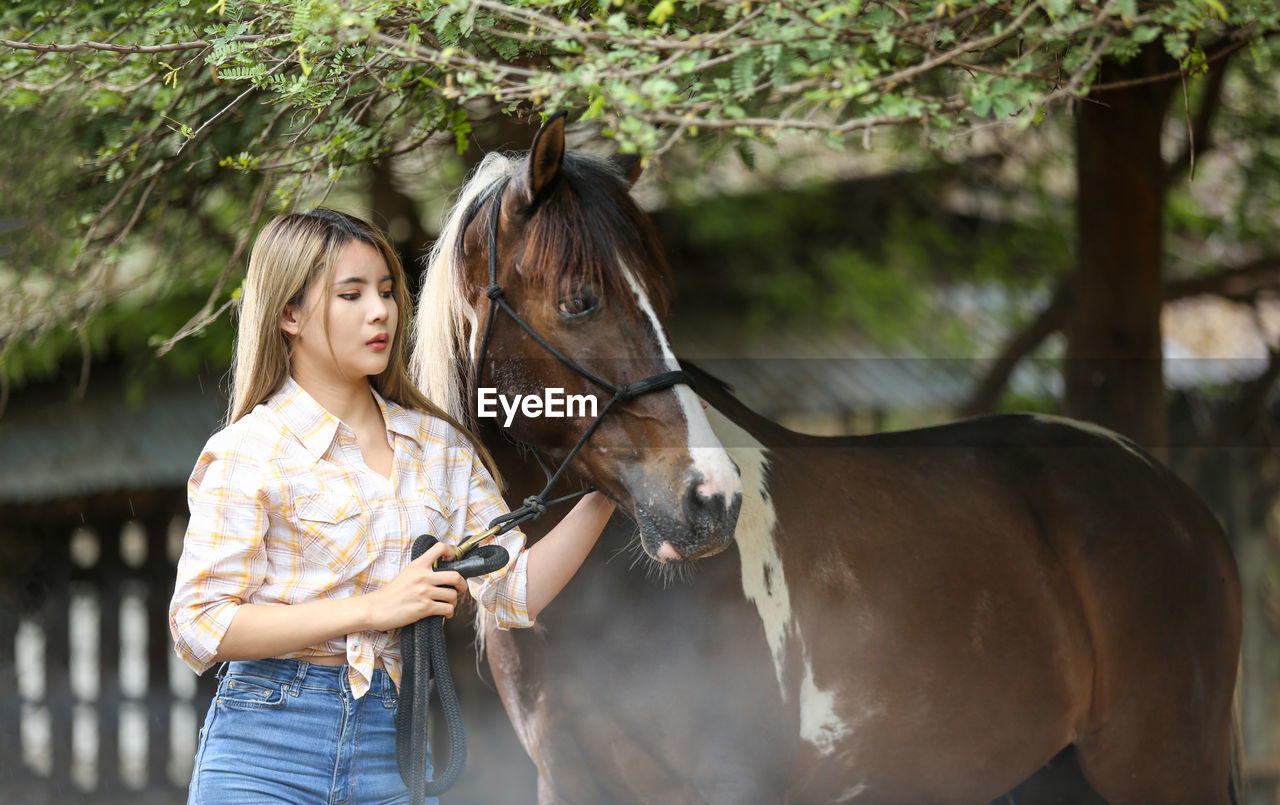 Woman with horse standing on field