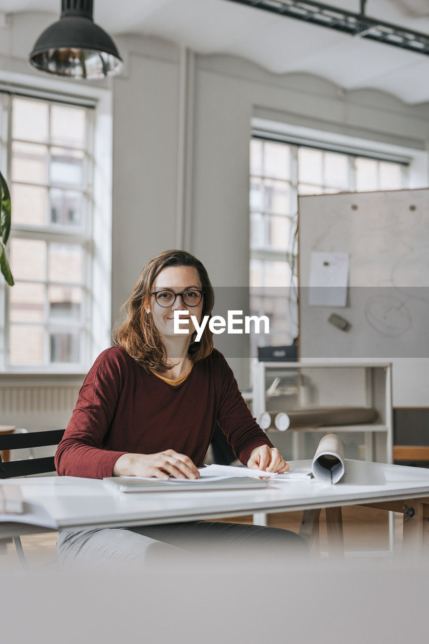 Portrait of smiling businesswoman sitting at desk in office