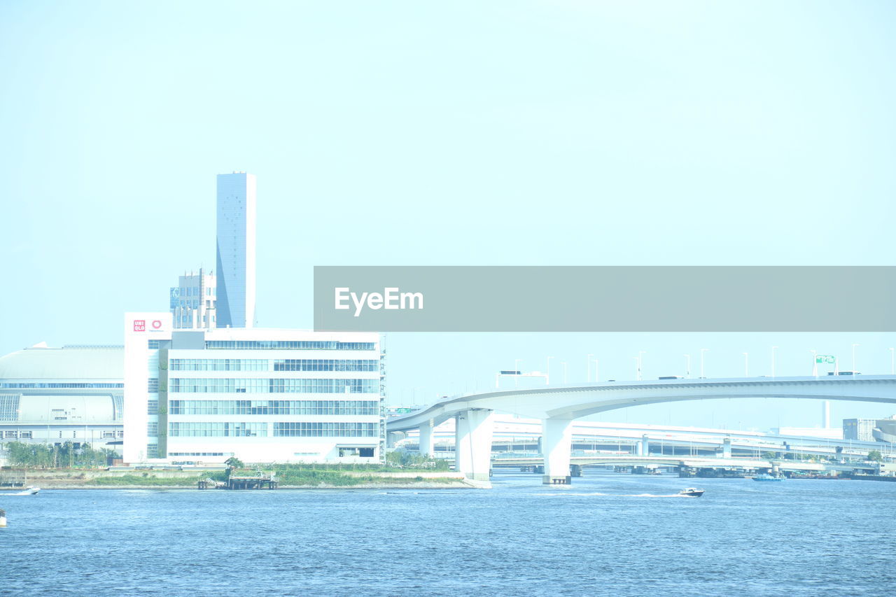 Bridge over river in city against clear sky