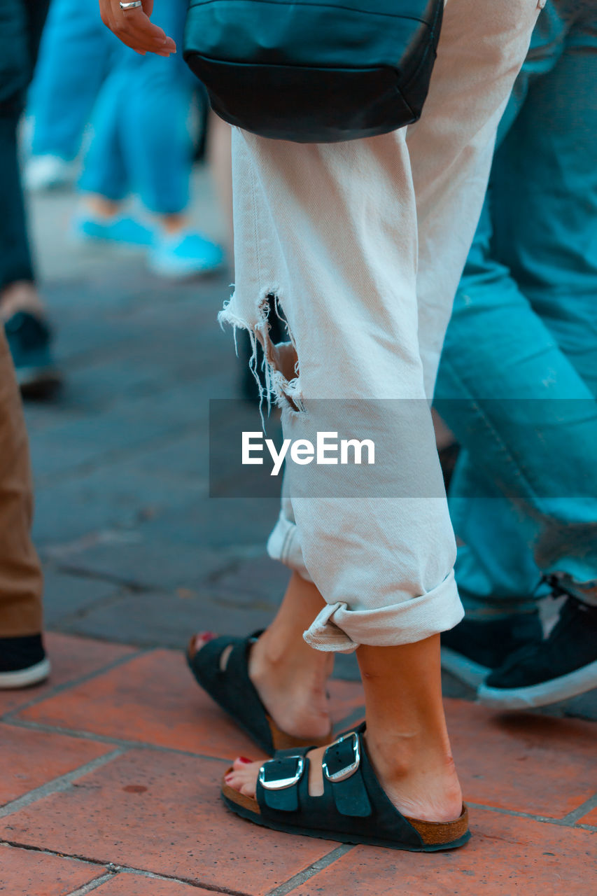 Low section of woman wearing torn pants while walking on street