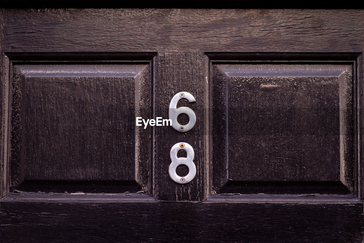 House number 68 on a dark wooden front door in london 