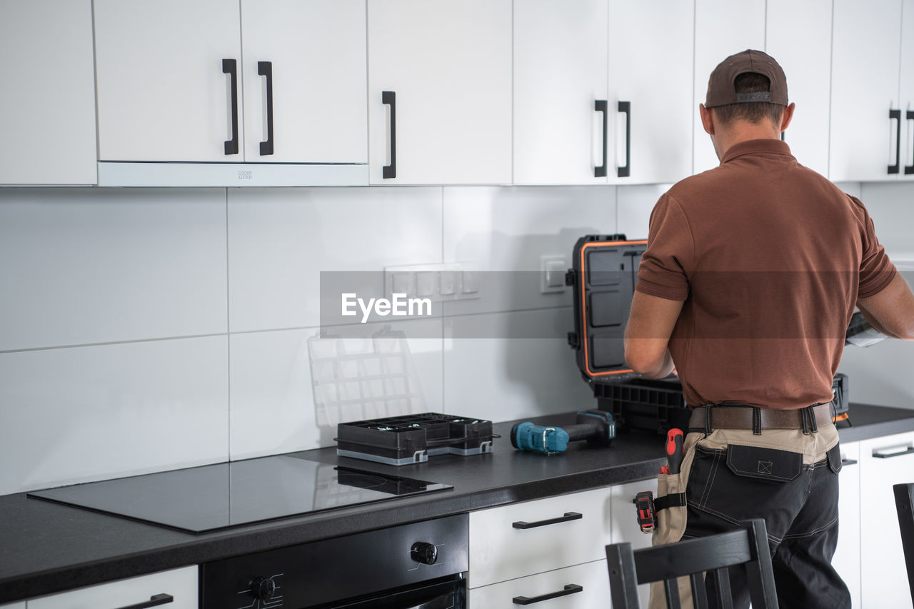 Rear view of repairman working at kitchen counter