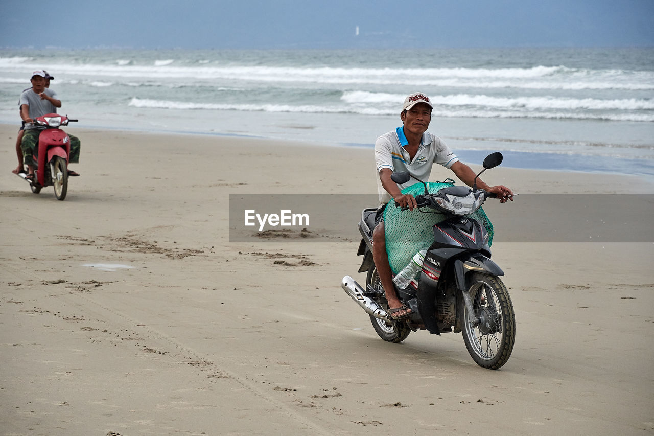 MAN RIDING BICYCLE ON BEACH
