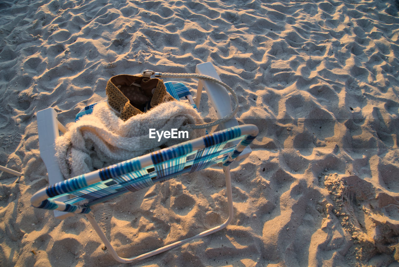 High angle view of chair and towel on sand at beach