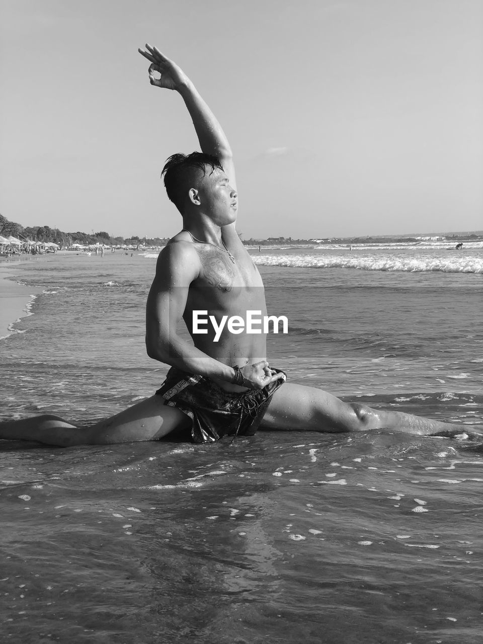 Shirtless man exercising in sea against sky