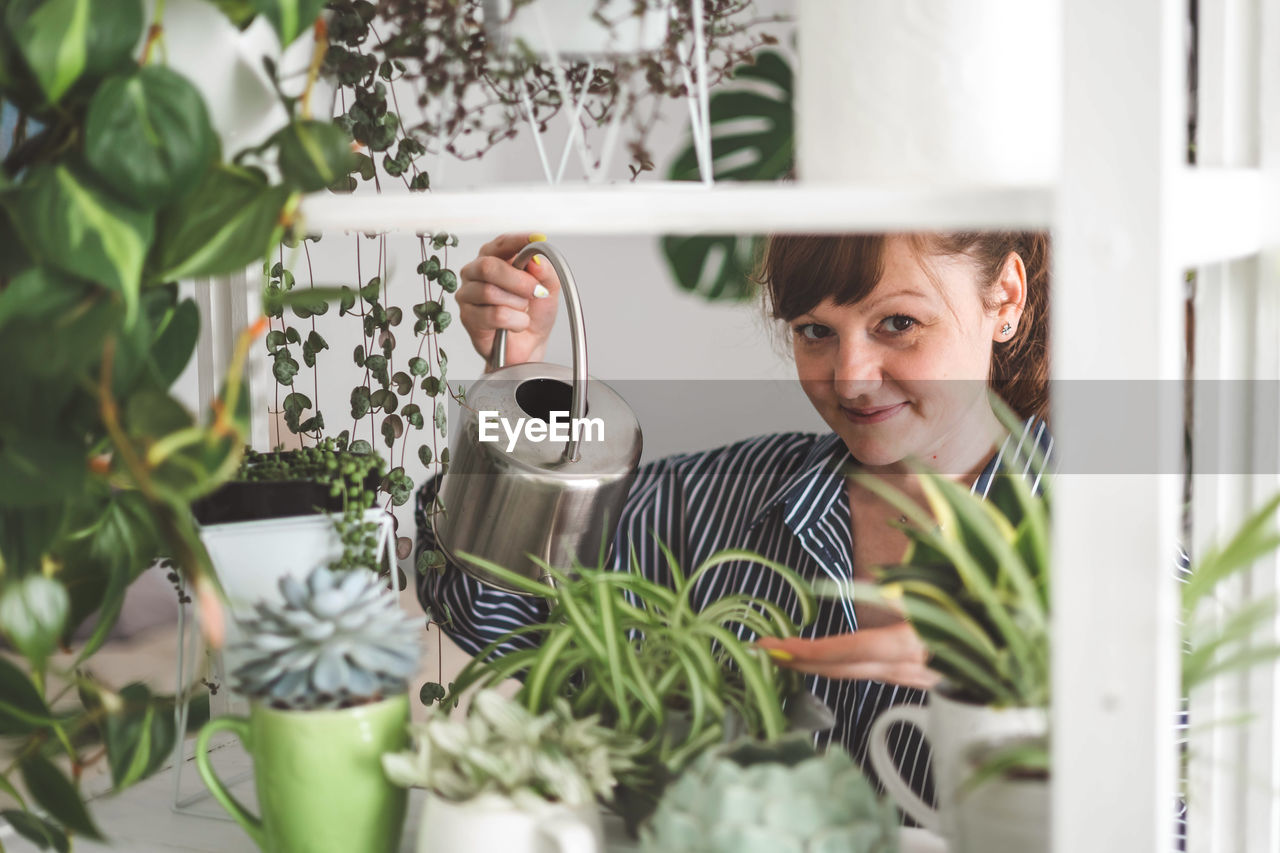 portrait of young woman looking through window sill