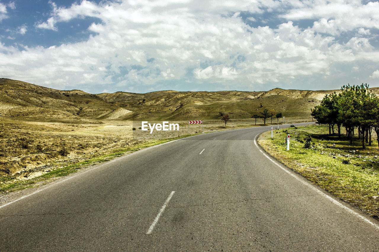 Road passing through landscape against sky